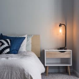 A bed and a lamp next to a nightstand.