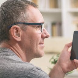 Man with a hearing aid using a smartphone