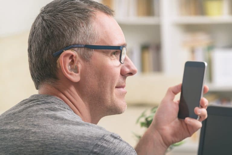 Man with a hearing aid using a smartphone